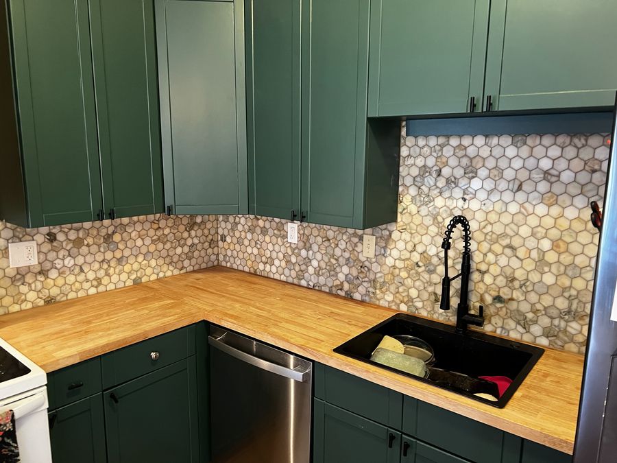 Kitchen cabinetry with wood counters and tile backsplash